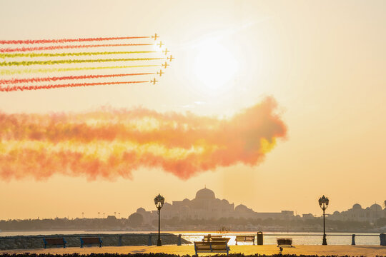 Air show with seven jet planes flying over presidential palace in Abu Dhabi paint the sky with flag colour in sunset. High quality photo
