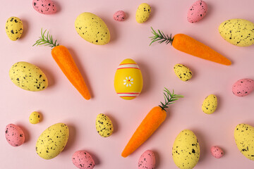 Creative Easter pattern of carrots and colorful eggs on pink background. Minimal Easter composition.Flat lay.