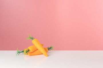 Toy carrots on white table. Minimal Easter or spring concept.