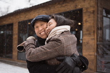 happy young asian couple hugging at walk in winter town