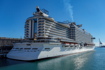 Big modern cruiseship or cruise ship liner Seaside Seaview in port with downtown Genoa skyline in...