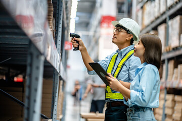 Warehouse staff working together using digital tablets to check the stock inventory on shelves in...