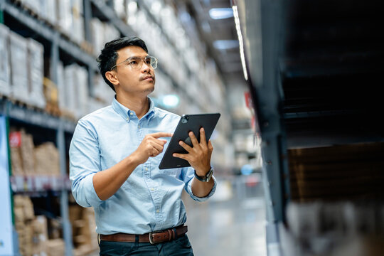 Businessman or supervisor uses a digital tablet to check the stock inventory in furniture large warehouses, a Smart warehouse management system, supply chain and logistic network technology concept.
