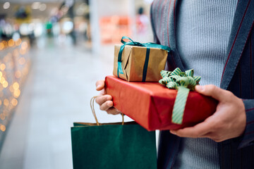 Close up of man with wrapped presents at shopping mall.