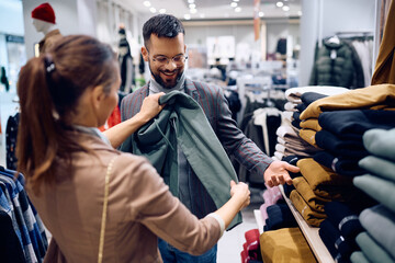 Happy man buying clothes with his girlfriend at shopping mall.