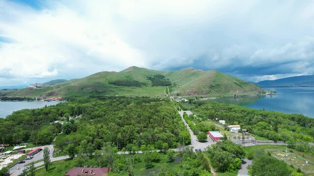  Aerial view  trees, mountain near lake. Drone fly over city near Sevan lake, Armenia. Famous, touristic place. 