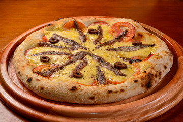 Aliche pizza on wooden table.