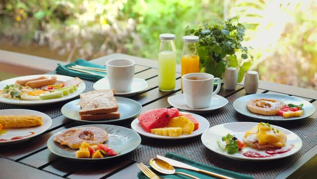 Variety of nutritious breakfast options served on outdoor patio table, complete with fresh fruits, beverages, and main courses. Healthy food and lifestyle.
