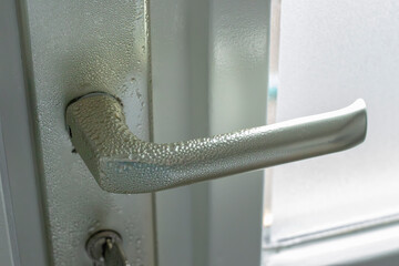 Condensation, moisture, on aluminum metal interior door hardware in cold winter season when heating...