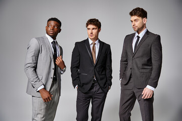 handsome stylish diverse male models in business elegant smart suits posing on gray backdrop