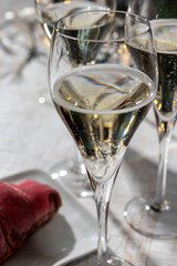 New year party, small bubbles of brut champagne cava or prosecco wine in tulip glasses with garland  lights on background