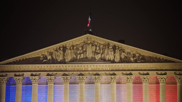 French National Assembly building with French flag at night. Architectural lighting of a building in the center of Paris