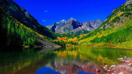 Tranquil forest with mountain range reflecting in calm lake
