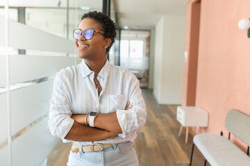 Determined inspired high-motivated African-American businesswoman standing near glass partition in...