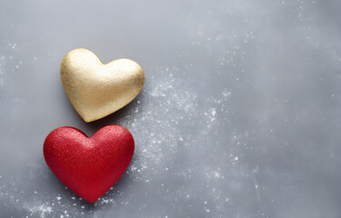 two red hearts shape and golden glitter on grey snowy background top view