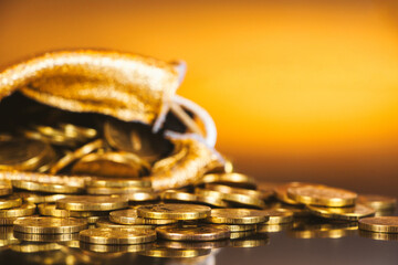 Gold coins in sack. Gold money on orange background. Copy space. A pile of coins .A bag with gold...
