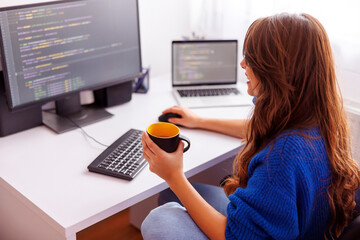 Female programmer drinking coffee while working in home office