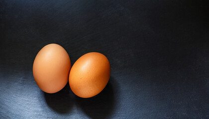 Two brown chicken eggs on a elegant composition, black background and with copy space