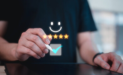 customer service satisfaction survey. man hand using pen tick mark on screen with gold five star and happy emotional face rating feedback