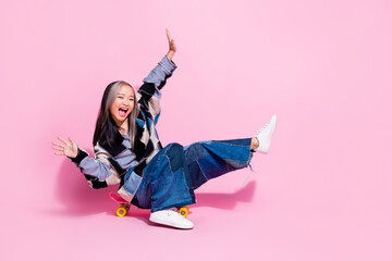 Full length photo of funny careless youngster wear oversize sweatshirt falling from skateboard scream isolated on pink color background © deagreez