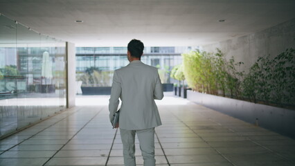 Business man strolling office corridor back view. Relaxed boss going to break