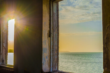 sea landscape and sun in the window of the destroyed room