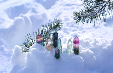 Crystals gemstones and pine branch in snow, winter background. set of minerals for esoteric Crystal Ritual, Witchcraft. spiritual energy practice for winter season. Winter magic - obrazy, fototapety, plakaty