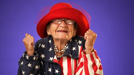 Closeup portrait of toothless elderly senior old woman with wrinkled skin having great happy success winner wearing US flag jacket isolated on purple background. People emotions concept.