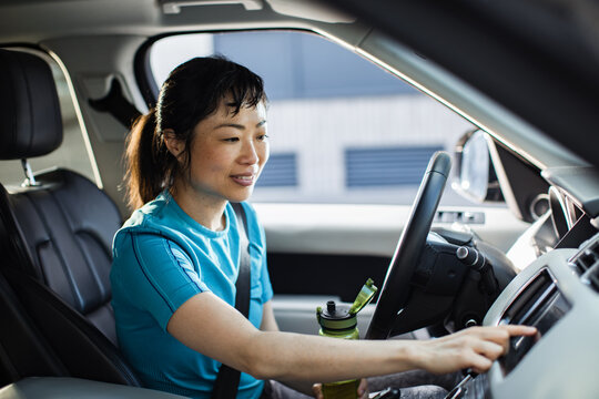 Asian Woman Hydrating While Sitting in Her Car