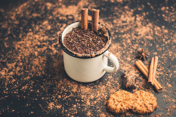 Homemade spicy hot chocolate drink with cinnamon stick, star anise, grated chocolate in enamel mug...