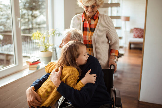 Caring little granddaughter with grandparents at home
