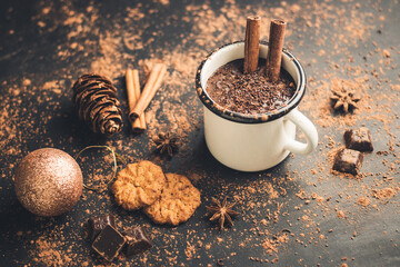 Homemade spicy hot chocolate drink with cinnamon stick, star anise, grated chocolate in enamel mug...