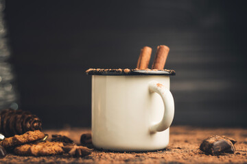 Homemade spicy hot chocolate drink with cinnamon stick, star anise, grated chocolate in enamel mug...