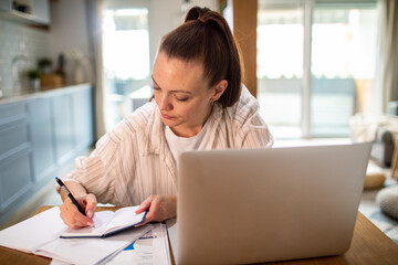 Thoughtful young woman working from home on laptop