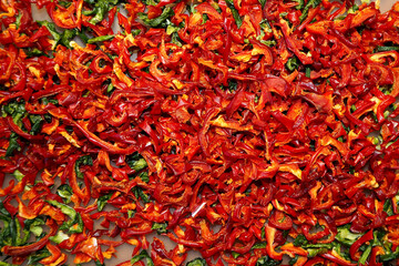 Fototapeta premium a lot of dried red and green bell peppers in an electric dryer. view from above. red and green food background