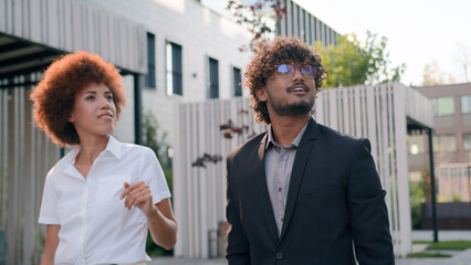 Urban building development manager Indian developer real estate realtor Arabian businessman presentation showing company outside to African businesswoman investor two diverse people partners in city