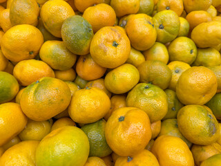 pile of fresh orange and green tangerine or mandarin fruits