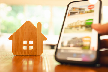 Model of a wooden house with a mobile phone showing the location of the new home. The idea of...