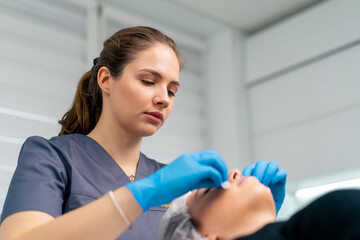 portrait of a beautician doctor cleaning a client's skin with a cotton sponge before starting a beauty and health procedure