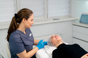 a cosmetologist gives instructions on how to care for a client's facial skin after a procedure in a...