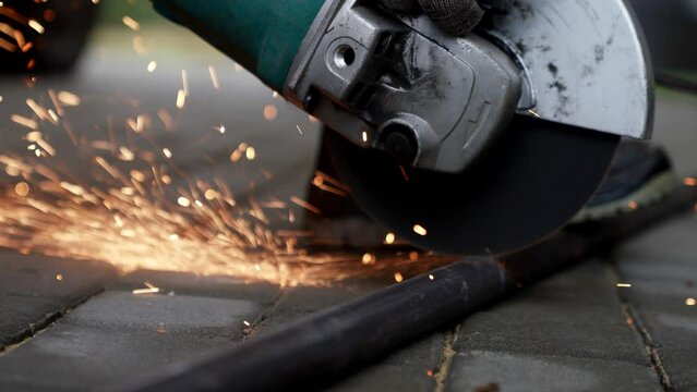 professional worker cutting metal pipe by circular saw, closeup view on construction site