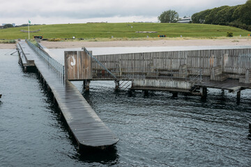 Kastrup Sobad, Copenhagen, Denmark, A round structure representing a swimming pool in the sea, which can be accessed via a walkway leading from the beach.