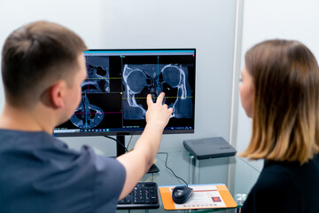 the radiologist doctor looks at the screen on which the 3D image of the nose scan shows the patient what needs to be changed during surgery