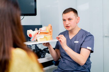 an ENT doctor consults a patient in the clinic's office tells about the possible consequences of...