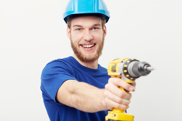 Construction man, portrait and power drill in hand, studio and maintenance by white background. Person, employee or small business owner with tools, helmet or happy for job at repair services company