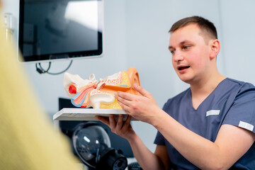an ENT doctor consults a patient in the clinic's office tells about the possible consequences of...