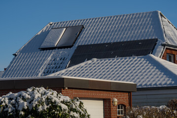 Solar water heater and solar power plant on a roof of residential house covered with snow. Solar...