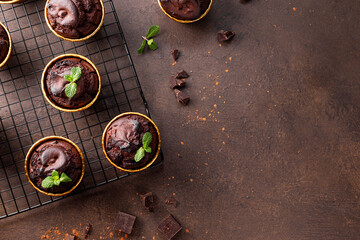 Chocolate brownie muffins with mint on dark background top view, copy space for text