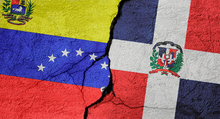 Fototapeta premium Venezuela and Dominican Republic flags on a stone wall with a crack, illustration of the concept of a global crisis in political and economic relations