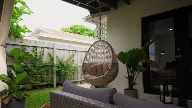 Cream colored hanging chairs in the tropical garden. Move camera footage